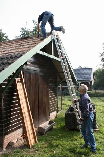 Geert Veenstra houdt een oogje in het zeil en een hand aan de ladder, als Hans Pinkster dakzitter wordt om pannen te leggen.
