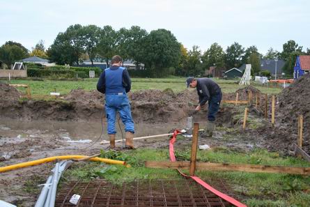 Twee gelaarsde bouwers zorgen ervoor dat het kandidaat-zwembad wordt veranderd in een bewerkbare bouwput. Elektrische pomp, met aandrijving vanuit de auto. Techniek? Je staat er versteld van!  