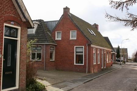Op de schijnbaar open plek links stond vroeger het winkeltje van Vrouw Helder. Helemaal links ten dele het woonhuis van de familie Miedema, waar vroeger o.a. de fam. W.Brilstra woonde. Verderop het dubbele woonhuis, waar, aan deze kant, jarenlang de familie Kloosterman heeft gewoond.  