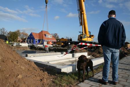 Man en hond bekijken het werk aan en op de Kooikavels aan de Meidoornstraat.  