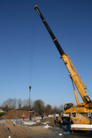 Met een grote hijskraan van Pol (Hoogeveen) worden prefab-vloerdelen op de juiste plaatsen gedeponeerd. Zowel bij de starterswoningen als de luxere landhuizen. Volgende stap.... 