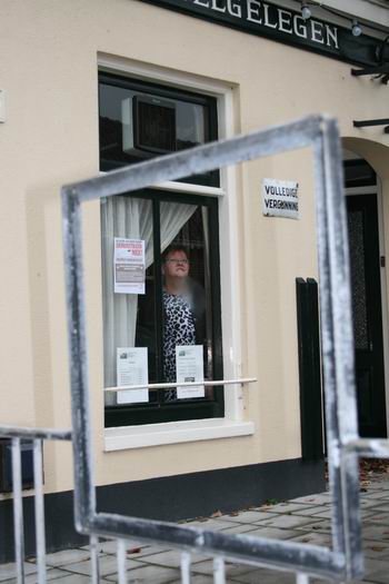 Niet iedereen kon de waterkou buiten even goed verdragen... Tieneke van der Veen houdt de boel in de gaten van achter het raam, benieuwd of de naam Welgelegen houdbaar blijkt...