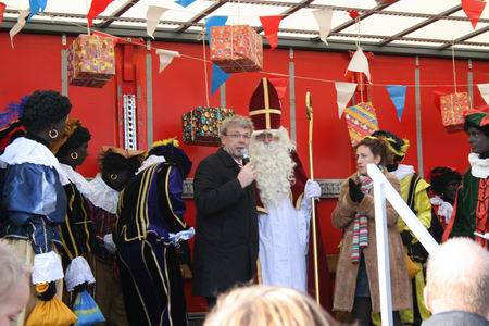 resize-of-sint-in-n-85-22112008 Heelhuids belandt Sint Nicolaas op het podium in beschermend gezelschap van zijn voetvolk, maar ook van wethouder Koos Wiersma en ceremoniejuf Iris Pijpker. Een liedje, Sinterklaas? Ja, doe maar Zie ginds komt de stoomboot.....