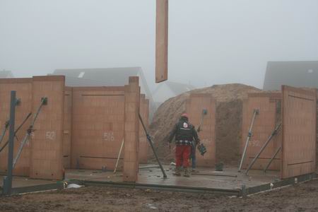 Als manna uit de hemel levert de kraanmachinist de prefabs deel voor deel af ter plekke. Vakkundig worden ze door twee gehelmde puzzelaars gemonteerd en gestut. 