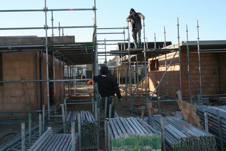 De steigerbouwers doen onverdroten hun koude klus. Koud? Nee, valt mee, als je maar bezig blijft... 