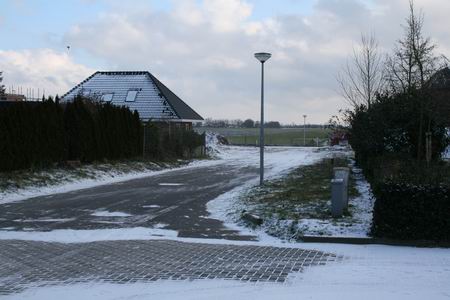 De snijdende oostenwind jaagt stuifsneeuw over het verlengde van de Kastanjestraat  
