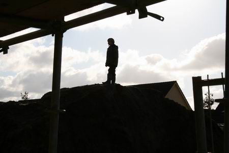 Tegenlicht aan de westkant van de Kooikavels, een jeugdige klauteraar heeft de top bereikt van een bult opgebrachte grond  