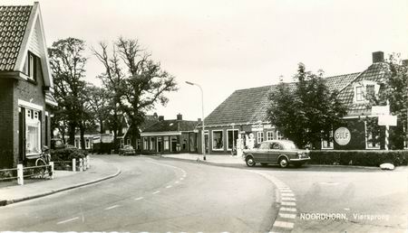 Foto waarschijnlijk genomen in 1964 of 1965. Rechts het tweewielerhuis met de ANWB-handwijzer, links het pand van Ter Maat, waar toen waarschijnlijk kapper Houwen zijn salon had. Op de achtergrond twee vrachtwagens van Van der Velde.