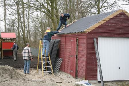 Het materiaalschuurtje wordt afgebouwd, het terrein op de achtergrond bij het speelobject ge-egaliseerd 