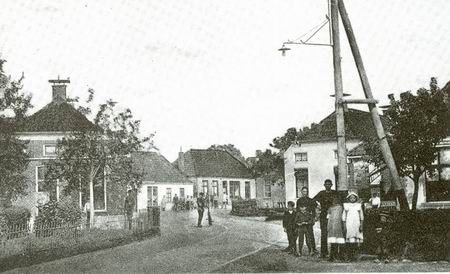 resize-of-langestraat90jaargeleden Ongeveer dezelfde situatie als op de foto hiervoor, alleen wel ongeveer 90 jaar geleden... Links Langestraat 14, achter de boompjes. De woning van smid Fokkens en zijn gezin. De smederij lag er tegenover. De lantaarnpaal stamt uit 1914, toen het electriciteitsnet in Noordhorn werd aangelegd. (Foto en informatie uit het boek GISTEREN VOOR DE LENS, blz.133)