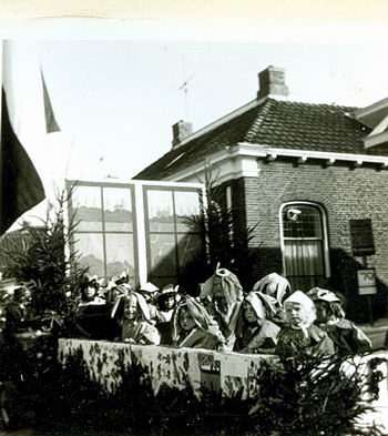 Zwart wit beeld uit een kleurrijke optocht in 1970. Wagen bij Paluno, toen daar nog een bushalte was, de GADO nog door het dorp reed... 