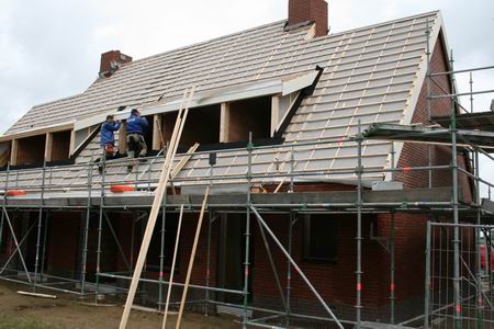 Henk en Co als ervaren dakhazen bezig met de afwerking van de landhuizen, de pannen liggen te wachten... 