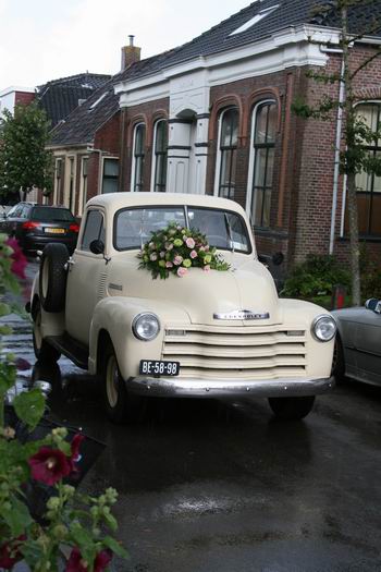 De bruidegom wordt zo te zien niet warm of koud van de ceremonie en rijdt zelf de fraaie Chevrolet naar de ingang van de NH-kerk. 