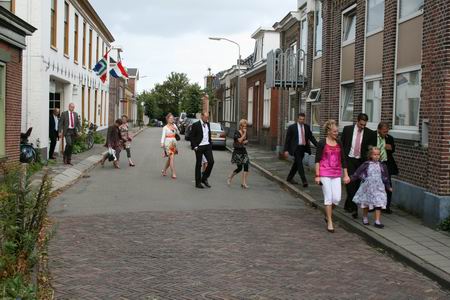 De eerste burgerlijke huwelijksvoltrekking op deze Noordhorner locatie is vlot verlopen; de bruiloftsgasten spoeden zich voor de kerkelijke inzegening naar de NH-kerk, aangespoord door wat regendruppels... 