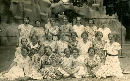 Jongedames, zomers fleurig, keurig in groepsordening. Maar waar? Wanneer? Wie????