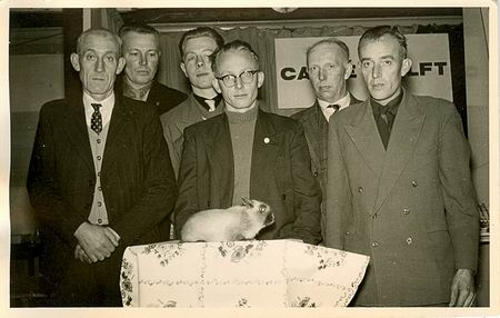 Wie zijn de konijnenfokkers en de keurmeester in het midden?