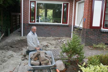 Kanaalwoningbewoner De Jong bezig met tuinstraatherstel, na de bouw van een nieuwe ruimte op de begane grond. Vermeldenswaard: de straatstenen zijn afkomstig van de directe kanaalwegaansluitingen op de N355. Deze directe aansluitingen sneuvelden in de jaren zeventig, vanaf dat moment moet er worden omgereden....