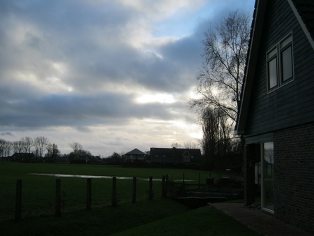 Niet zo'n geslaagde foto, maar ik wil hem toch laten zien. We zijn achter de woonboerderij langs gelopen en gestopt bij het pand waarin Jikky tot en met 2011 haar winkel en atelier had. In de verte de nieuwbouw achter de oude Chr.MAVO, de plek van de familie Kok. Daar 'ergens'  komt het toekomstige N355-tunnelverkeer weer bovengronds....