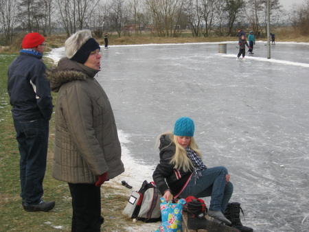Oma Dien Homan laat zich door de snijdende wind niet weerhouden van een kijkje bij de ijsbaan. Een kleindochter heeft het intussen wel bekeken...
