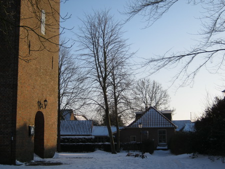 Spelend zonlicht bij de toren van de NH-kerk. Door het kappen van de zieke kastanje komt het huisje van de familie W. de Vries mooier uit!
