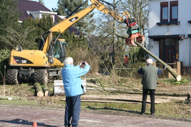 De publieke belangstelling is niet groot, maar enkele buurtbewoners leggen het gebeurde fotografisch vast.