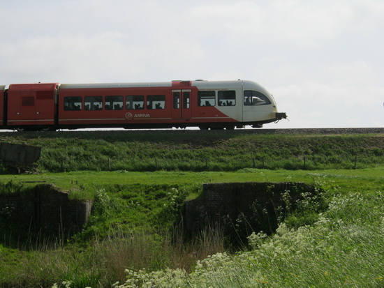 Een Arrivatrein op weg naar Leeuwarden passeert de plekken waar de resten van de oude spoorbrug over de Schipsloot (nog....) zichtbaar zijn.