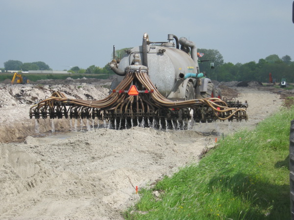 Nee, aan de kanaalkant van de spoorbaan wordt het nieuwe tracé van de kanaalweg niét geïnjecteerd met vloeibare mest.... Het zand op het nieuwe tracé wordt nat gemaakt, anders ligt het met de harde wind binnen de kortste keren in het kanaalwater... Moet er nog meer worden gebaggerd...