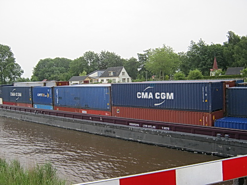 Bij de brug tussen Noord- en Zuidhorn is te zien waarom de vaarweg Lemmer-Delfzijl dient te worden verruimd: Een containerschip van 3275 vaart westwaarts. Lengte 110 meter! (En ik heb er al eens eentje van 3297 t. gezien...)