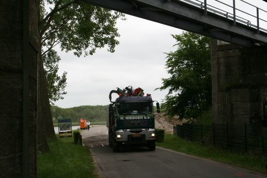 Van verre is te zien dat er een grote diversiteit aan bezigheden valt waar te nemen, achter de spoorbrug. Een drukte van belang, ieder zijn taak, een geoliede machine!