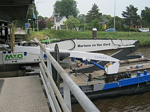Een binnenvaarder vervoert een nieuwe machine richting oost... Situatie op 5 juli bij de brug tussen Noord- en Zuidhorn, aan de zuidkant...