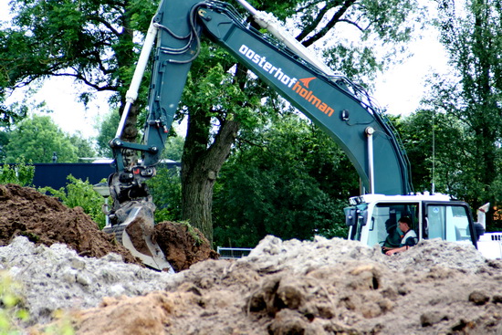 Bezige kraanmachinist op het terrein waar de nieuwe rotonde wordt gerealiseerd. Enorme bulten grond, onwerkelijk landschap...