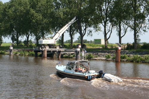 Een plezierboot, met hoge snelheid voorbijvarend... Schipper met ontbloot bovenlijf, het 'bruinen' gaat nog niet al te snel...