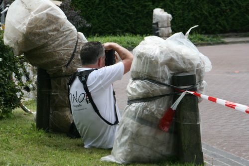 Sportfotograaf Gino, op de rug gezien, veilig tussen twee strobalen....