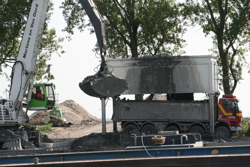 Aan de zuidkant is de kraanmachinist druk bezig de laatste happen grond uit de boot in de bak te deponeren. Vrachtauto eronder, kleppen open, vrachtauto vol, wegrijden..... Volgende!