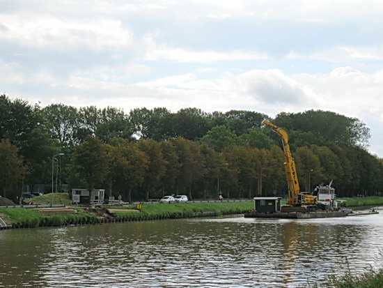 Als ik, het wachten moe, al bijna bij de brug ben, zie ik (soms heb je ogen achter in je hoofd....) dat er een vlot met kraan naderbij vaart. Gauw terug!
