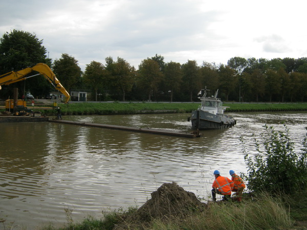 Even een adempauze voor Mulder & Co, even kijken naar de collega-kanaalwerkers aan de overkant.... Met de "Hendrik" wordt een smal, langgerekt drijvend "iets" naast de ponton met kraan gedirigeerd.