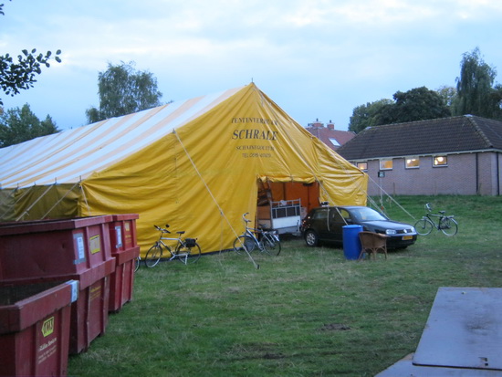 Daar staat ie, de grote tent! Binnen wordt druk gewerkt aan de presentatie van de diverse gebruikte goederen. In "De Wegwijzer" brandt licht, ook daar wordt de boekenmarkt goed voorbereid.