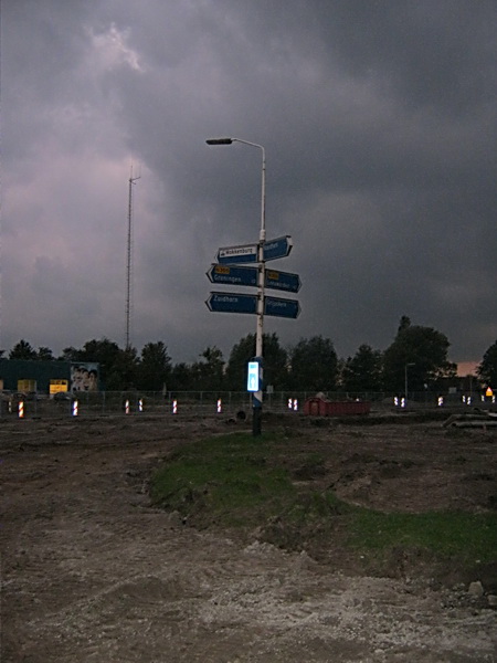 Vanavond langs het tunnelterrein, inmiddels afgeschermd met hekken. Zie ik ineens de ANWB-wegwijzer in niemandsland staan....