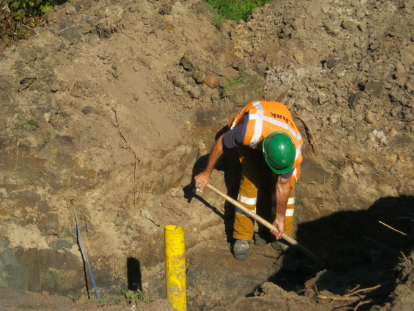 Op de hoek van de Transportweg en de Mokkenburgweg is een HAK-werknemer in een diep gat bezig met "iets aangaande de waterleiding".  Moet ook verderop aan de Mokkenburgweg. 