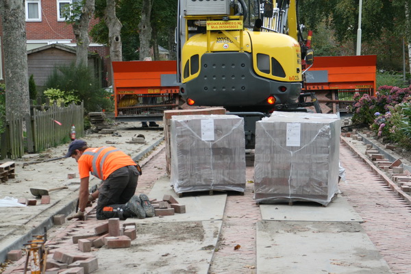 De Norritsstraat vanaf de Noordwijkweg. Een moderne, snelle manier om een straat over de hele breedte in een keer te beleggen. Alleen de kanten, daar komt ouderwets handwerk aan te pas. Het nieuwe trottoir ligt er al, en de goten ook. Opknapbeurt van de Norritsstraat, rioleringsleed bijna geleden...