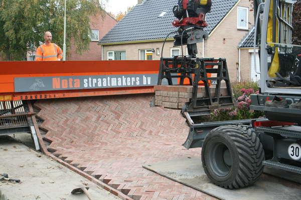 Achter de machine de vlotte klaarlegger van de stenen in de machine. Staande te doen, niet meer op de knieën....