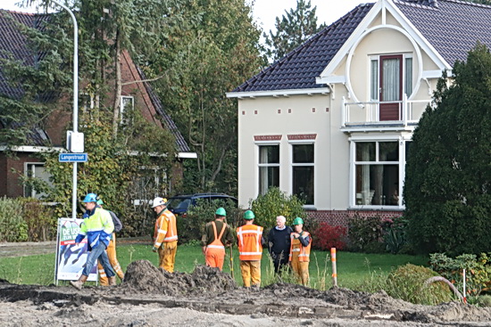 Overleg in de open lucht tussen wegverleggers en buurman aan de noordkant, Kruisinga. 