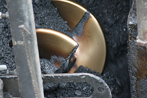 Een geweldige schroef draait het asfalt uit de voorraadbak naar de te beleggen weg. Mooi stukje techniek.... Of maalt ie ook??!