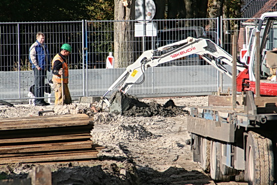 Maar er wordt ook nog gegraven, gezocht naar oude leidingen? Gemeten... Zuidema, met hond, kijkt belangstellend toe, aan de veilige kant van het hek!