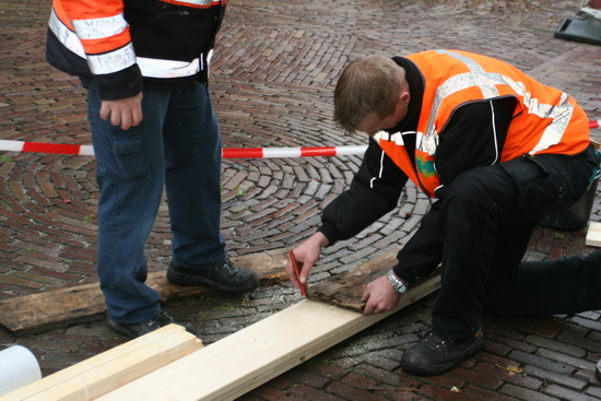 Geconcentreerd wordt het hout afgemeten en gezaagd. Het woord "koffie" valt.... 