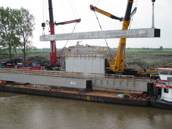 De eerste korte ligger wordt behoedzaam op zijn plaats gelegd, tussen pijler en landhoofden aan de zuidkant van de NVH-brug